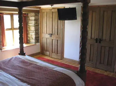 a bedroom with a bed with a television on the wall at Haye Barton Farm in Liskeard