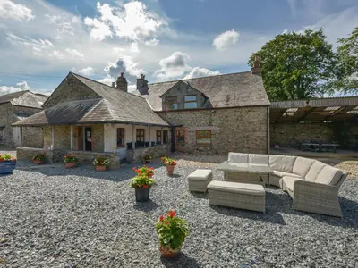 a patio with couches and flowers in front of a house at Haye Barton Farm in Liskeard