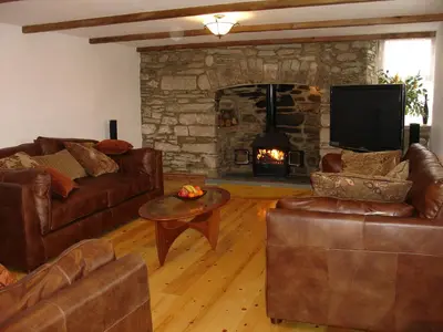 a living room with leather furniture and a stone fireplace at Haye Barton Farm in Liskeard