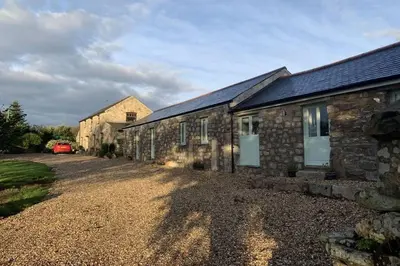a stone building with a car parked next to it at Cart Shed Cottage in Truro