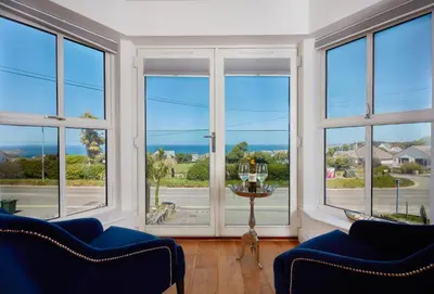 a living room with large windows with a view of the ocean at 5 Four Seasons in Carbis Bay