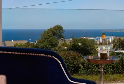 a wine glass sitting on a table with a view of the ocean at 5 Four Seasons in Carbis Bay