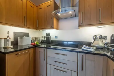 a kitchen with wooden cabinets and black counter tops at 5 Four Seasons in Carbis Bay