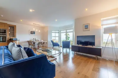 a living room with a blue couch and a television at 5 Four Seasons in Carbis Bay