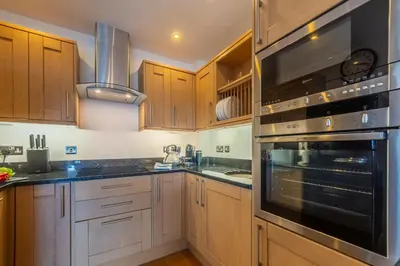 a kitchen with wooden cabinets and a stove top oven at 5 Four Seasons in Carbis Bay