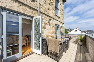 a patio with a sliding glass door and a balcony at 5 Fernhill in Carbis Bay