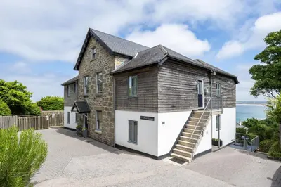 an old stone house with white doors and stairs at 5 Fernhill in Carbis Bay