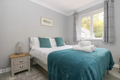 a white bedroom with a bed and a window at Compass Point in Falmouth