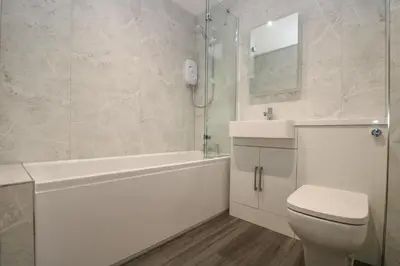 a white bathroom with a tub and a toilet and a sink at Compass Point in Falmouth