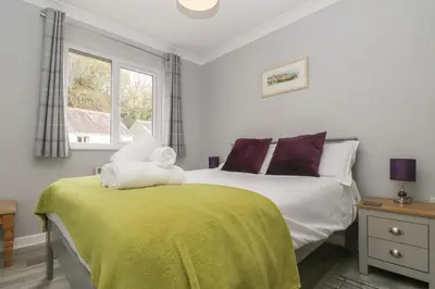 a bedroom with a bed with a yellow blanket and a window at Compass Point in Falmouth