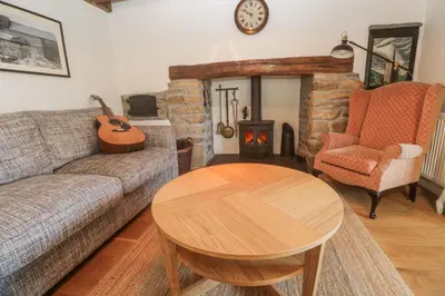 a living room with a couch and a table and a wood stove at Kernyk in Helston