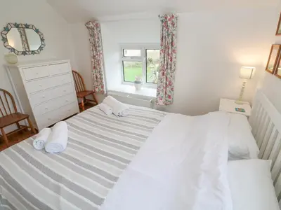 a bedroom with a white bed and a window at Kernyk in Helston