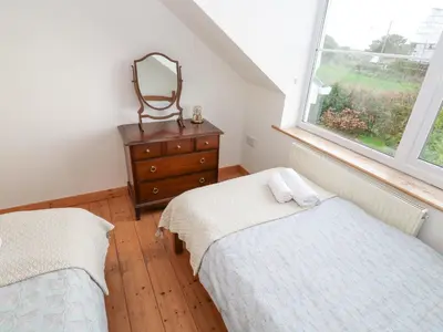 a bedroom with two beds and a mirror and a dresser at Kernyk in Helston