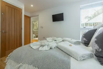 a white bed with white towels on top of it at 3 Sandy Lane in Carbis Bay