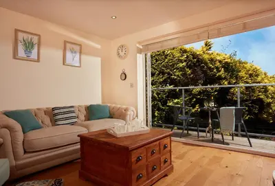 a living room with a couch and a large window at 6 Sandy Lane in Carbis Bay