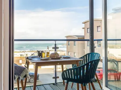 a table and chairs on a balcony with a view of the ocean at Fistral Waves in Crantock