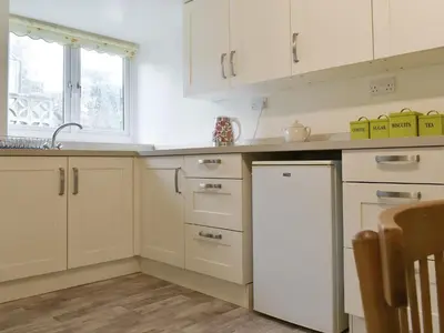 a kitchen with white cabinets and a refrigerator at Millys Nook in St Austell