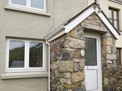 a house with a white door and a stone wall at Millys Nook in St Austell