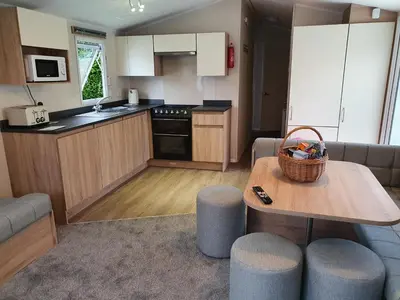 a small kitchen with a table and a couch at Cozy 3 bedroom Caravan, Sleeps 8, at Parkdean Newquay Holiday Park in Newquay