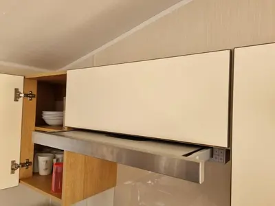 a kitchen with a white cabinet with a shelf at Cozy 3 bedroom Caravan, Sleeps 8, at Parkdean Newquay Holiday Park in Newquay