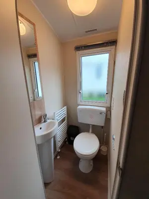 a small bathroom with a toilet and a sink at Cozy 3 bedroom Caravan, Sleeps 8, at Parkdean Newquay Holiday Park in Newquay