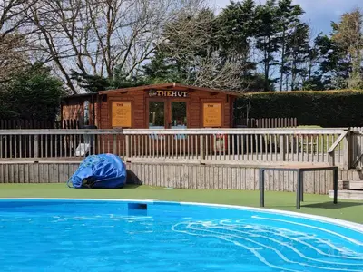 a swimming pool with a house in the background at Cozy 3 bedroom Caravan, Sleeps 8, at Parkdean Newquay Holiday Park in Newquay