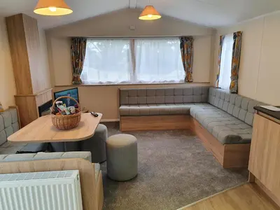 a living room with a couch and a table at Cozy 3 bedroom Caravan, Sleeps 8, at Parkdean Newquay Holiday Park in Newquay