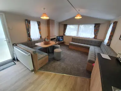 a living room with a couch and a table at Cozy 3 bedroom Caravan, Sleeps 8, at Parkdean Newquay Holiday Park in Newquay