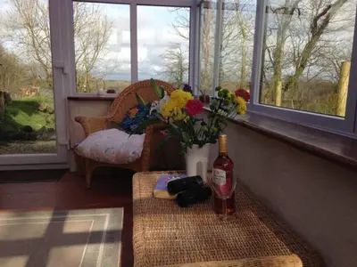 a table with a bottle of wine and flowers on it at Cottage Barn, Jacobstow in Bude