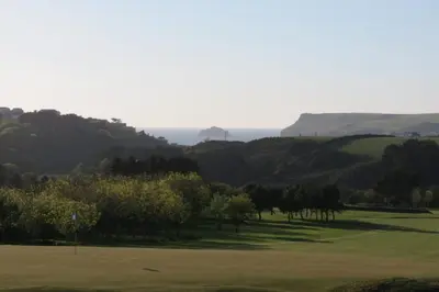 a golf course with trees and the ocean in the background at Cottage Barn, Jacobstow in Bude