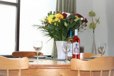 a table with a bottle of wine and a vase of flowers at Cottage Barn, Jacobstow in Bude