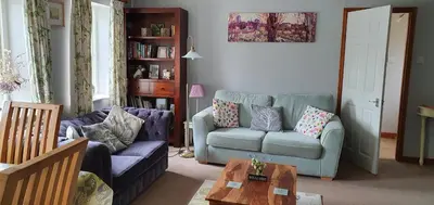 a living room with two couches and a table at Mimi's Cottage in Liskeard