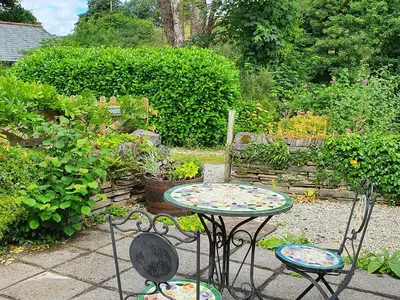 a table and two chairs in a garden at Mimi's Cottage in Liskeard