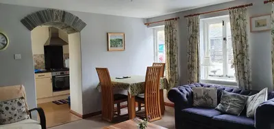 a living room with a table and a blue couch at Mimi's Cottage in Liskeard