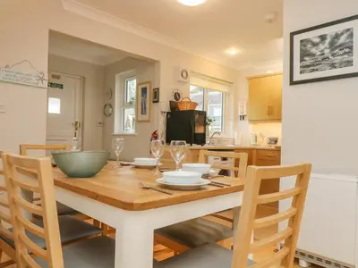 a kitchen and dining room with a wooden table and chairs at Oyster Cottage in Falmouth