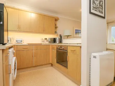 a kitchen with wooden cabinets and a white appliance at Oyster Cottage in Falmouth