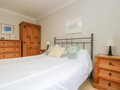 a bedroom with a large white bed and a wooden dresser at Oyster Cottage in Falmouth