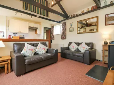 a living room with two leather couches and a table at Bowling Green Cottage in Redruth