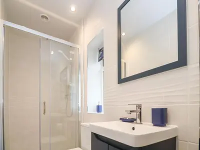 a white bathroom with a sink and a shower at Bowling Green Cottage in Redruth