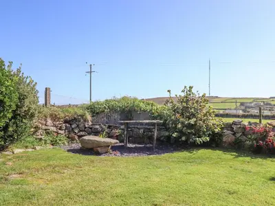 a bench in a garden with a stone wall at Bowling Green Cottage in Redruth