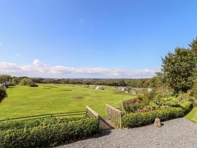 a large grassy field with a staircase leading to a garden at Valley View in Helston