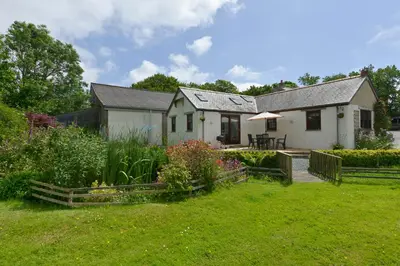 a white house with a garden in front of it at Valley View in Helston