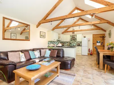 a living room with a leather couch and a table at Valley View in Helston