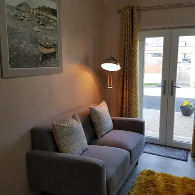 a living room with a couch and a sliding glass door at Chynoweth Court in Newquay