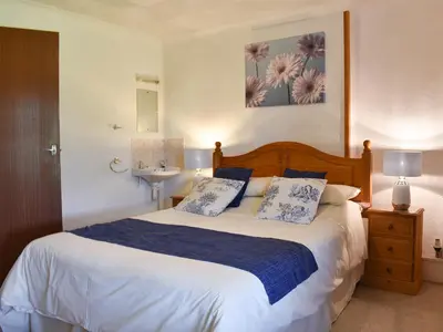 a bedroom with a large bed with blue and white pillows at Holly - Ukc4243 in Lanreath