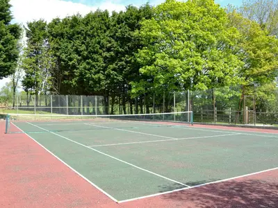 a tennis court with a net and some trees at Hayloft - Ukc4241 in Lanreath