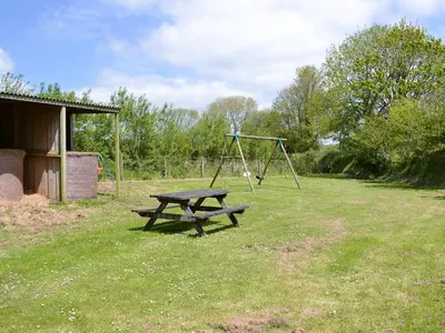 a picnic table and swing set in a field at Hayloft - Ukc4241 in Lanreath