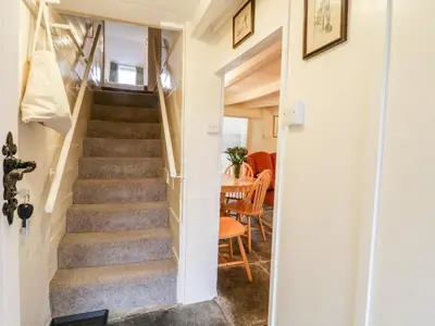 a staircase leading up to a dining room with a table at 2 Rose Cottages in Looe