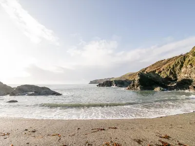 a sandy beach with rocks in the water at 4 Rose Cottages in Looe