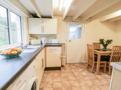 a kitchen with a sink and a bowl of fruit on the counter at 4 Rose Cottages in Looe